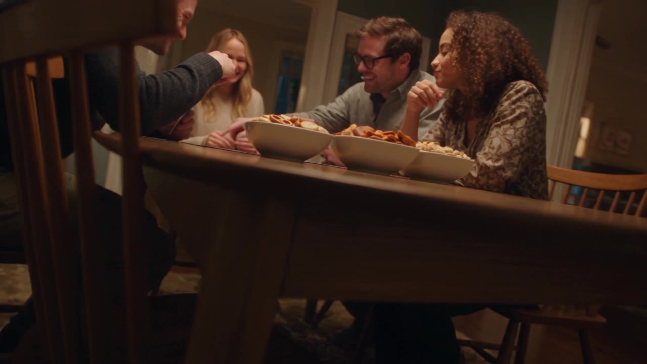 Familie und Freunde lachen gemeinsam bei einem Spieleabend mit zwei CrackersCompany Snackmischungen