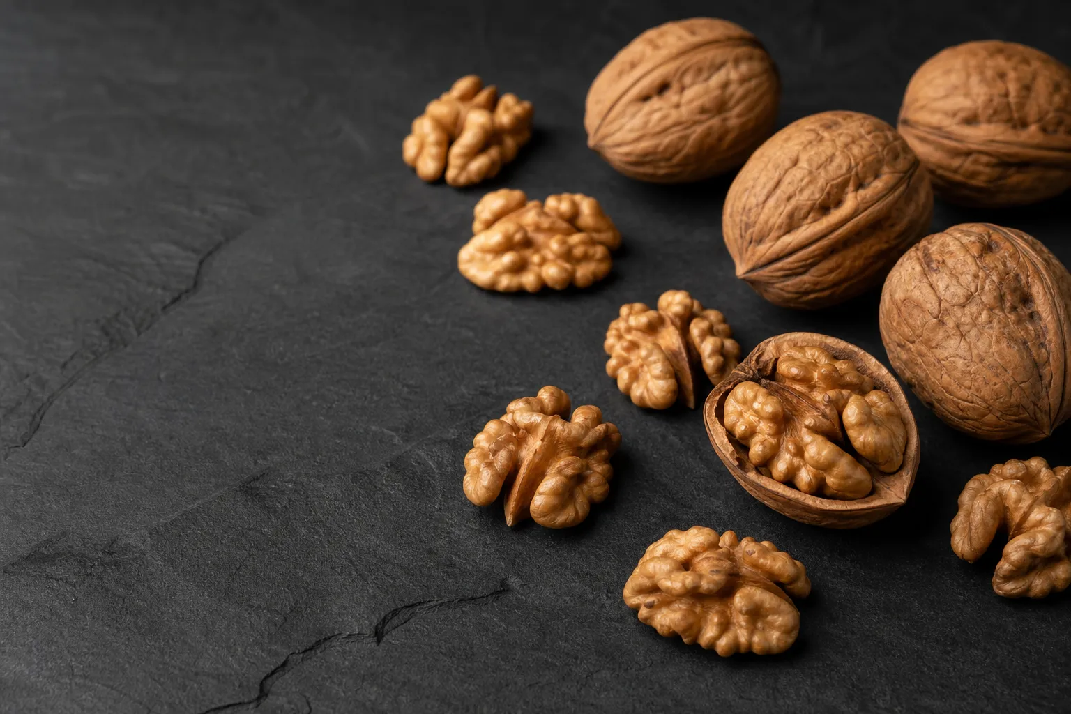 Walnuts and walnut kernels on dark slate